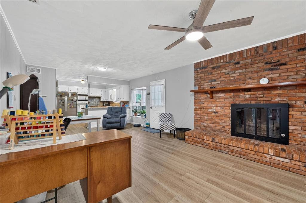 9700 Brookwood Circle, Woodway, TX 76712 Brick fireplace with a wood-finish mantel and a black-framed insert