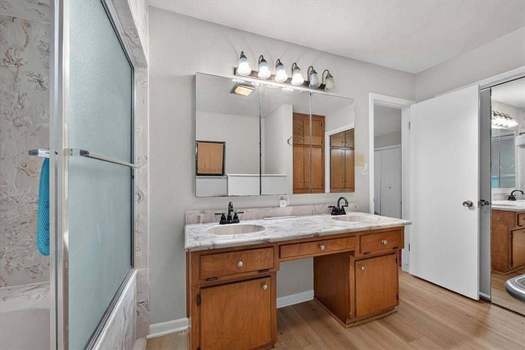 9700 Brookwood Circle, Woodway, TX 76712 Double vanity with integrated sinks, granite-look countertop, and wood-finish cabinetry