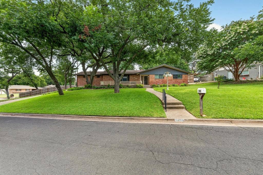 9700 Brookwood Circle, Woodway, TX 76712 Brick and siding home featuring a front lawn with mature trees and a concrete walkway