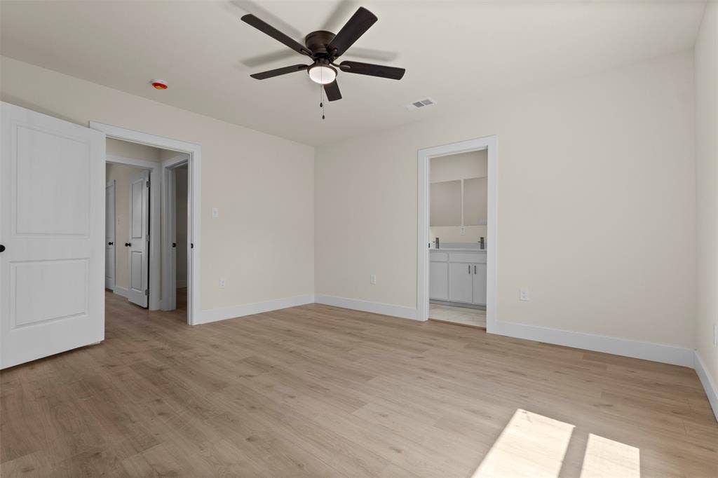 1104 S Brighton Avenue, Dallas, TX 75208 Light wood-finish flooring, white walls, dark ceiling fan with integrated lighting, and white interior doors with dark hardware