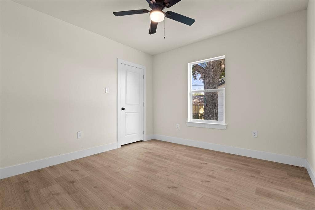 1104 S Brighton Avenue, Dallas, TX 75208 Wood-finish flooring, neutral wall tones, ceiling fan with light, white trim, and a paneled door