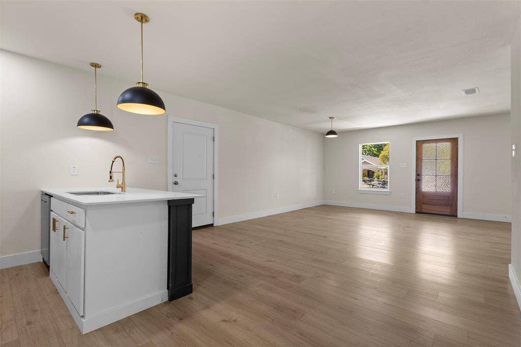 1104 S Brighton Avenue, Dallas, TX 75208 Kitchen island with white cabinetry, gold-tone hardware, and an undermount sink
