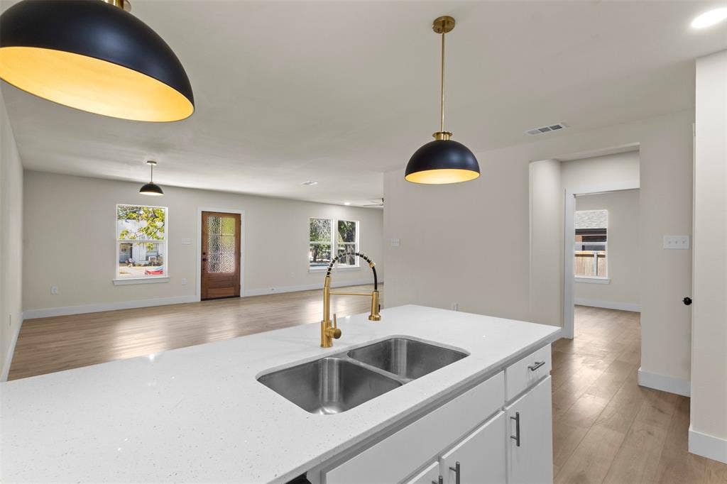 1104 S Brighton Avenue, Dallas, TX 75208 Kitchen island with a double basin stainless steel sink, gold-finish faucet, and white quartz countertop