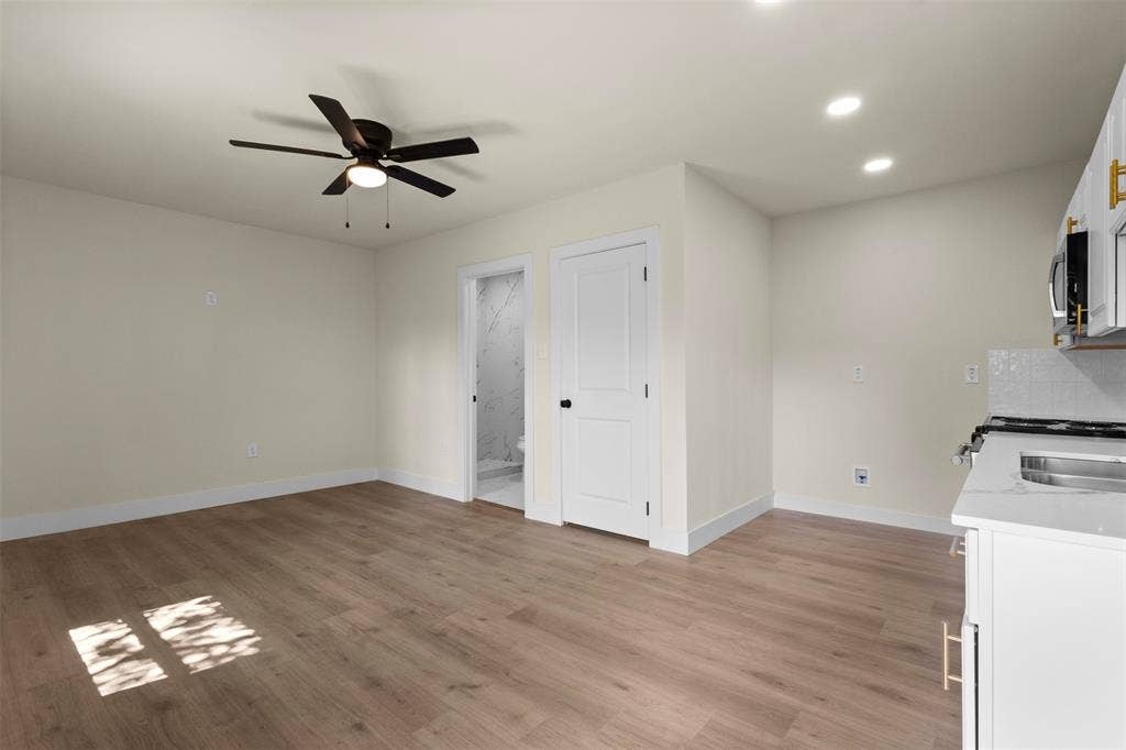 1104 S Brighton Avenue, Dallas, TX 75208 Light wood-finish flooring with a ceiling fan, recessed lighting, and a white flat-panel door