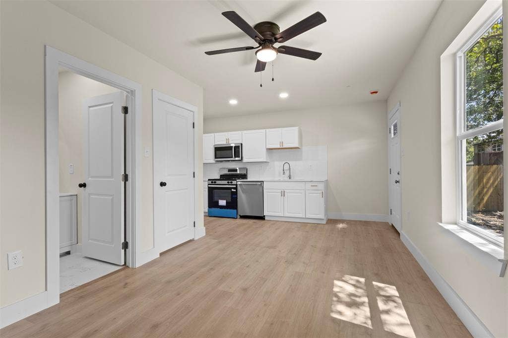 1104 S Brighton Avenue, Dallas, TX 75208 Open-concept living space with wood-finish flooring, a contemporary ceiling fan, and white kitchen cabinetry