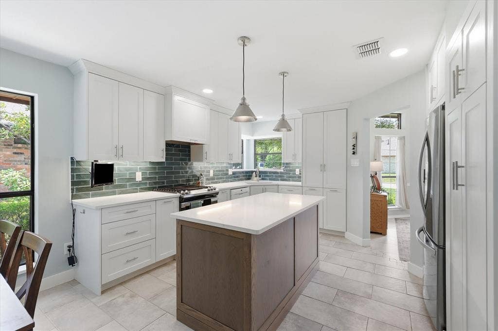642 Eagle Drive, Coppell, TX 75019 Completely updated kitchen featuring white quartz countertops with slight veining which allows the dark greenish blue subway tile to stand out.