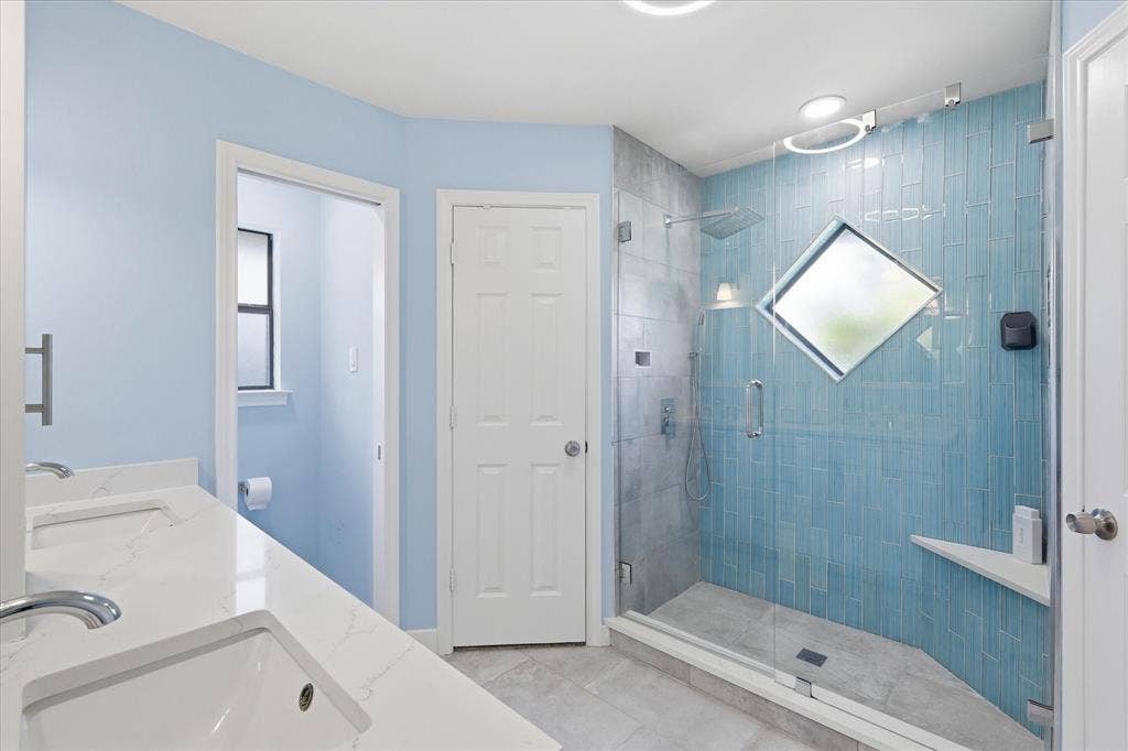 642 Eagle Drive, Coppell, TX 75019 Updated primary bathroom. Roomy walk in shower with pretty blue tiles to resemble a waterfall. Bath also features his and hers walk in closets.