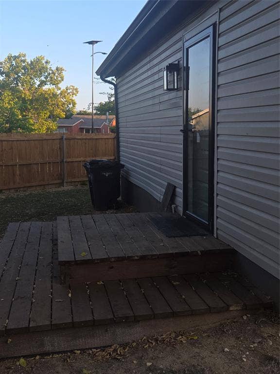 2329 Cass Street, Fort Worth, TX 76112 Exterior siding in a neutral tone features a black-framed glass door with an exterior lantern light fixture
