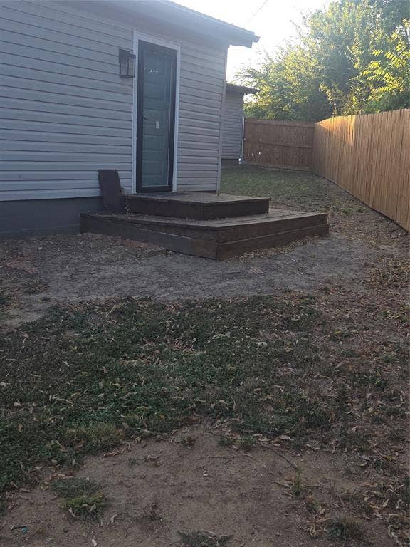 2329 Cass Street, Fort Worth, TX 76112 Rear exterior featuring horizontal siding, a wooden deck with two steps, and a privacy fence