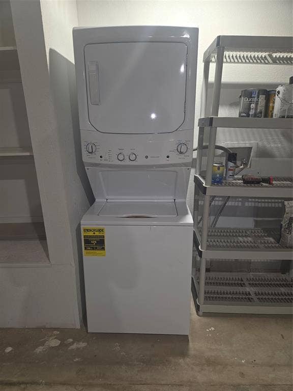 2329 Cass Street, Fort Worth, TX 76112 Dedicated utility area featuring a white stackable washer and dryer unit, built-in shelving, and a concrete floor