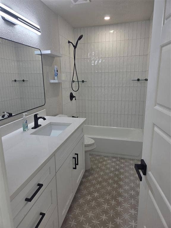 2329 Cass Street, Fort Worth, TX 76112 Bathroom featuring a white vanity with integrated sink, matte black fixtures, patterned floor tile, white subway tile shower surround, and a white bathtub