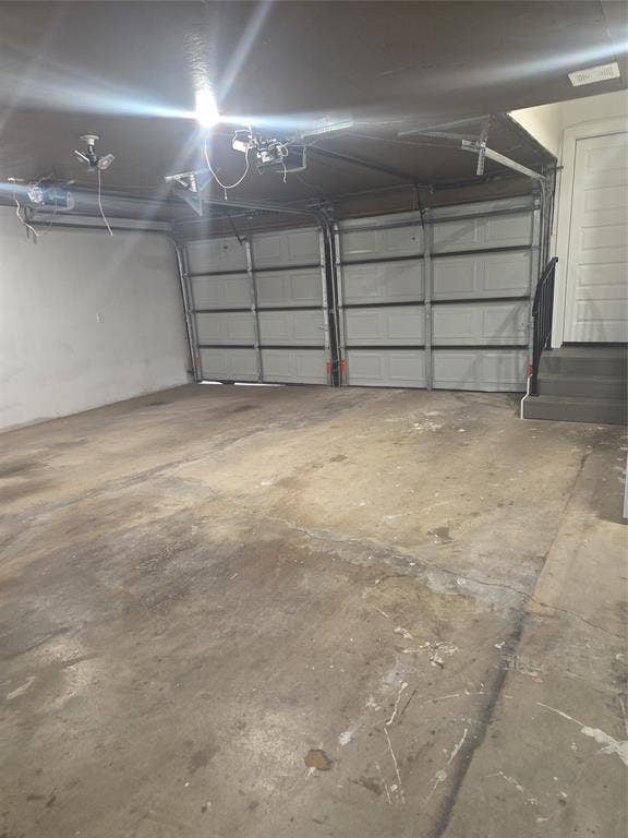 2329 Cass Street, Fort Worth, TX 76112 Two-bay garage featuring concrete flooring, overhead lighting, and an interior access door with steps