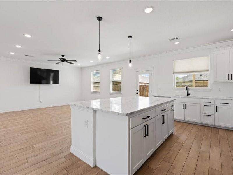 5528 Mesa Loop, Granbury, TX 76048 Modern kitchen island featuring a white countertop, two pendant lights, and ample storage cabinetry