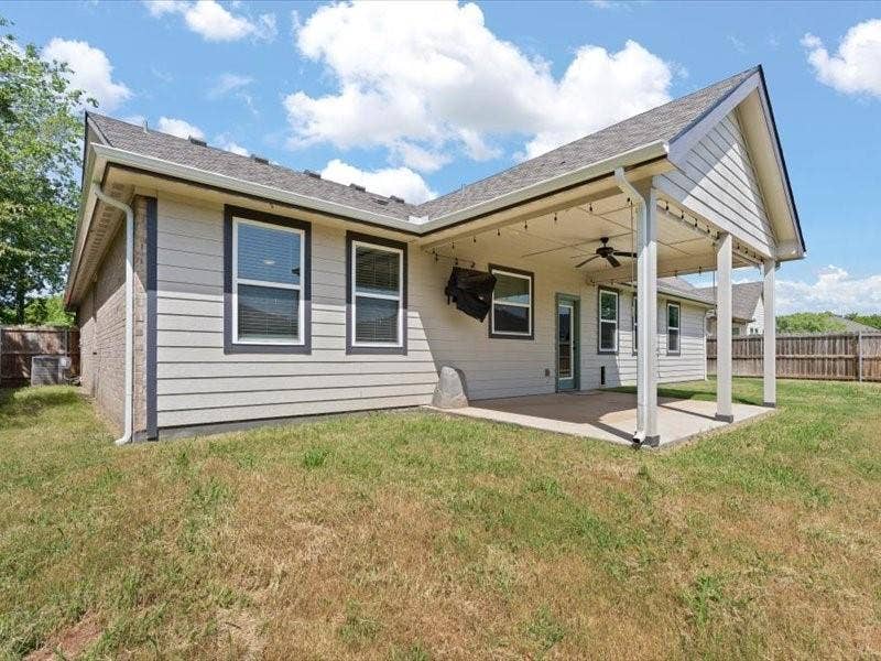 5528 Mesa Loop, Granbury, TX 76048 Rear exterior with covered patio featuring a ceiling fan and string lighting