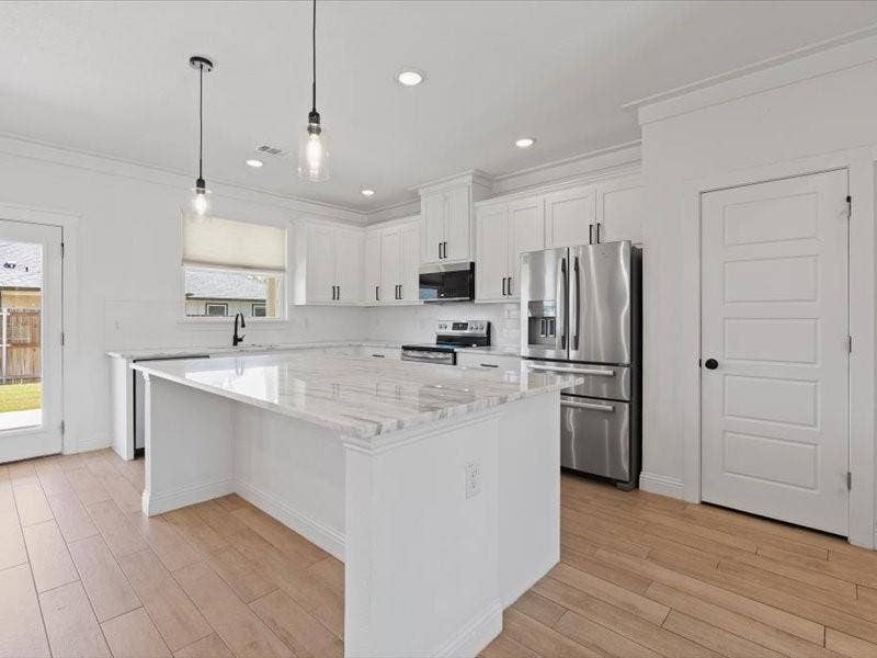 5528 Mesa Loop, Granbury, TX 76048 Modern kitchen featuring an expansive center island with a stone countertop, white shaker cabinetry, stainless steel appliances, and wood-finish flooring