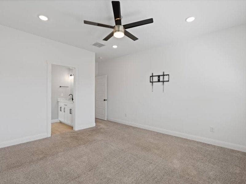 5528 Mesa Loop, Granbury, TX 76048 Spacious carpeted room featuring a ceiling fan with integrated lighting, recessed lighting, and a doorway revealing a vanity with a dark faucet and a wall-mounted towel rack
