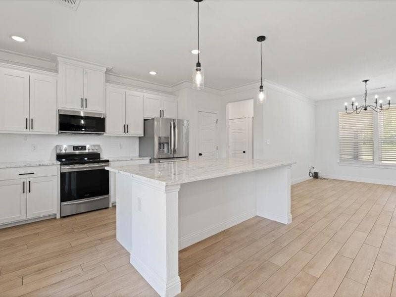 5528 Mesa Loop, Granbury, TX 76048 Open concept kitchen featuring an island with a light-toned countertop, white cabinetry with dark hardware, stainless steel appliances, and wood-finish flooring