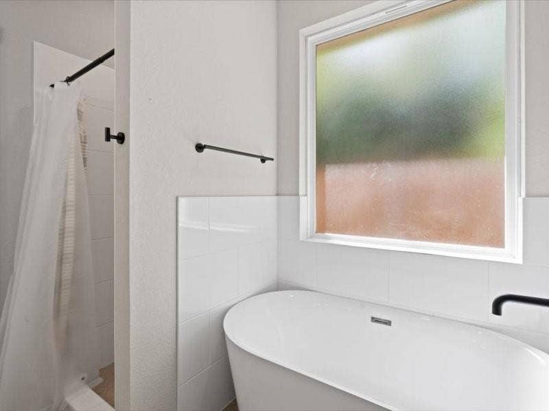 5528 Mesa Loop, Granbury, TX 76048 Freestanding soaking tub with a matte black wall-mounted faucet, complemented by a white tiled wall surround and a frosted window