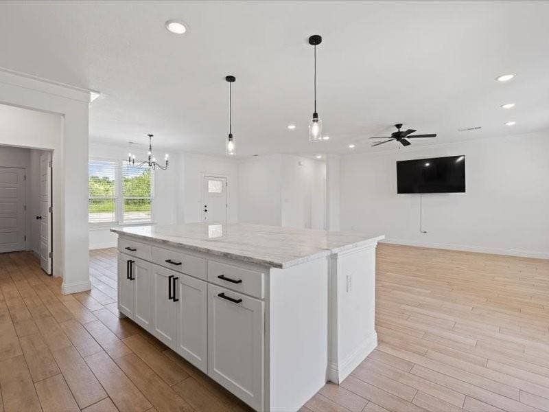 5528 Mesa Loop, Granbury, TX 76048 Kitchen island featuring white cabinetry, dark hardware, and a light-toned stone countertop