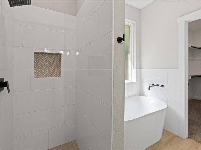 5528 Mesa Loop, Granbury, TX 76048 Shower with white subway tile surround and a herringbone-patterned tile niche, complemented by a freestanding soaking tub with wall-mounted matte black fixtures