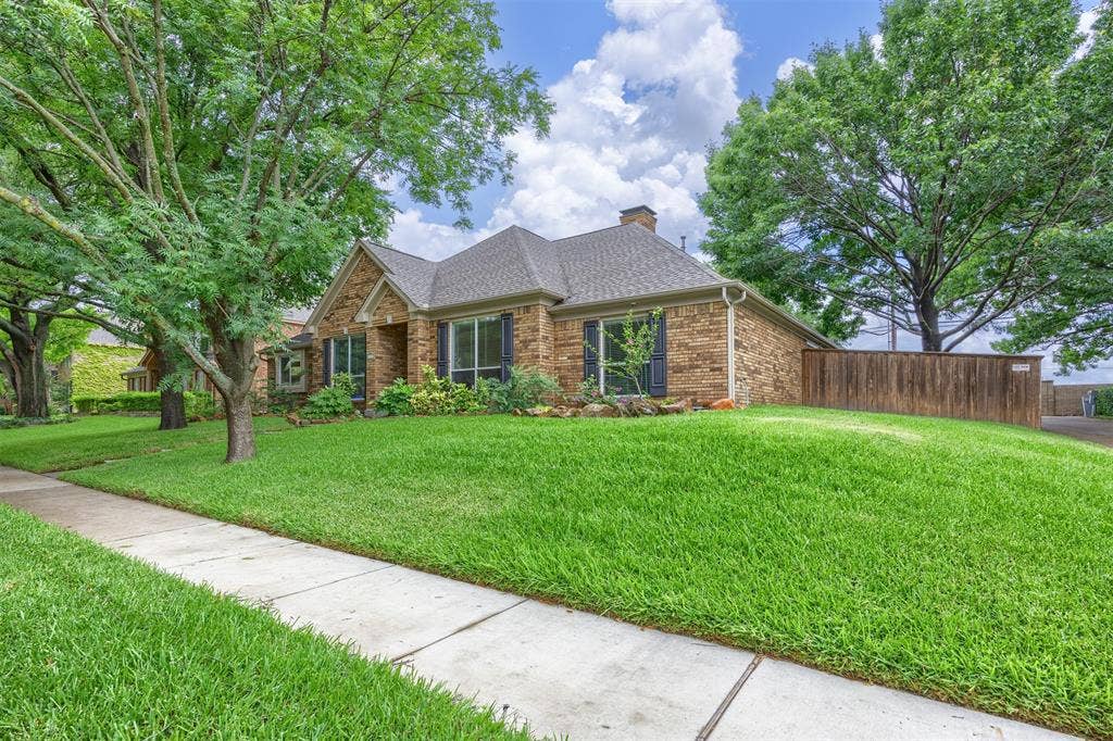 1717 Whitney Drive, Richardson, TX 75082 Brick exterior residence featuring a gabled roof and dark shingle roofing