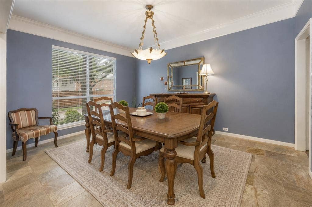1717 Whitney Drive, Richardson, TX 75082 Formal dining area featuring a large window with horizontal blinds, crown molding, and stone-look tile flooring