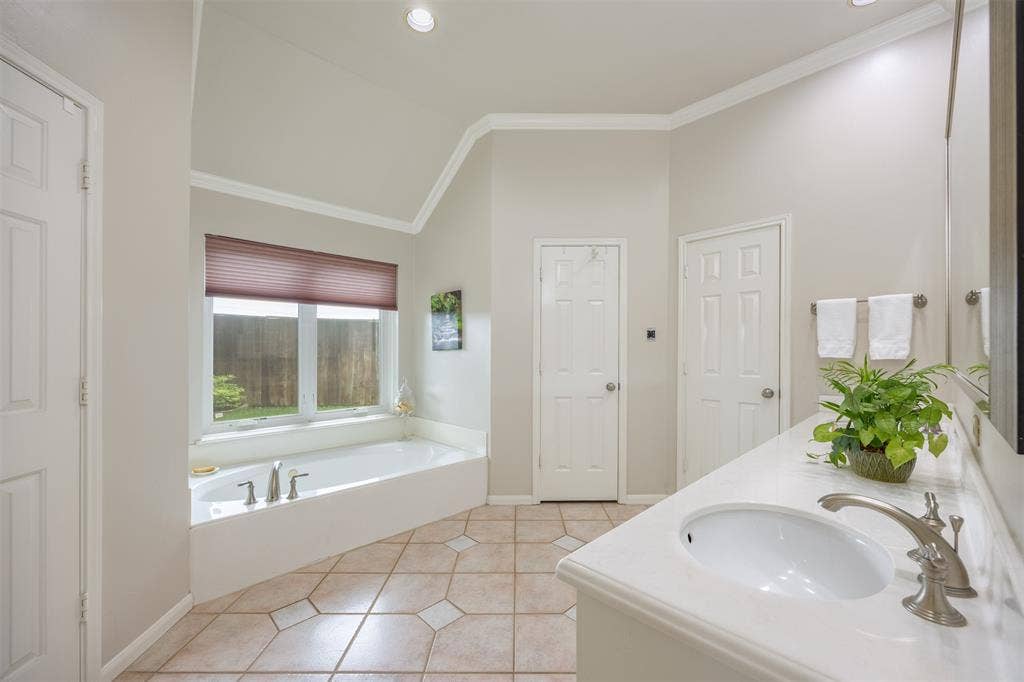 1717 Whitney Drive, Richardson, TX 75082 Bathroom featuring a large soaking tub with window, tile flooring, vanity with integrated sink, and vaulted ceiling with recessed lighting