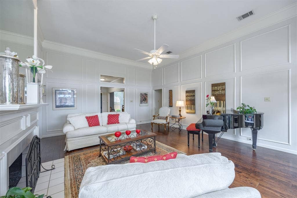 1717 Whitney Drive, Richardson, TX 75082 Spacious living area featuring extensive wall molding, wood-finish flooring, a white mantel, and a ceiling fan with light fixture