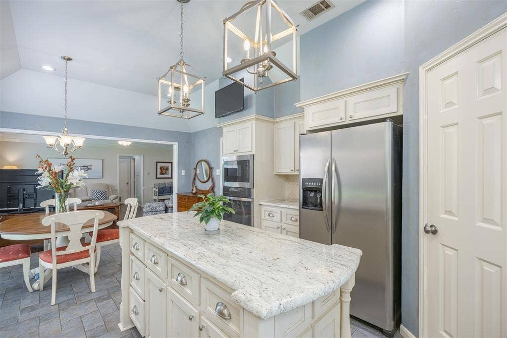 1717 Whitney Drive, Richardson, TX 75082 Kitchen featuring a central island with a light-toned countertop, stainless steel refrigerator, and double wall ovens