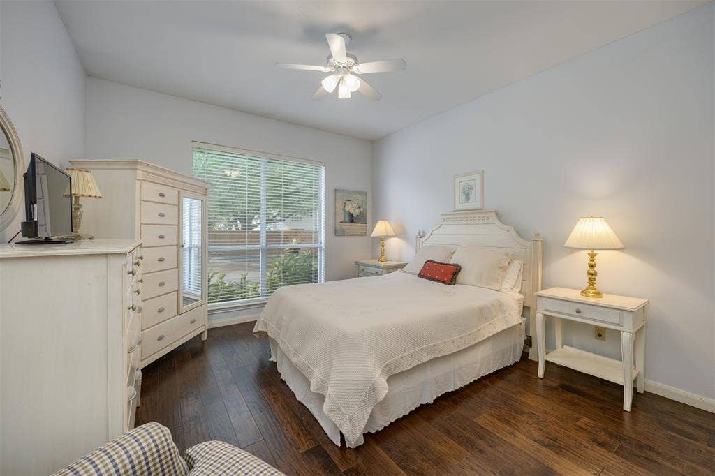 1717 Whitney Drive, Richardson, TX 75082 Bedroom featuring rich wood-finish flooring, a large window with horizontal blinds, a white ceiling fan, and a vaulted ceiling