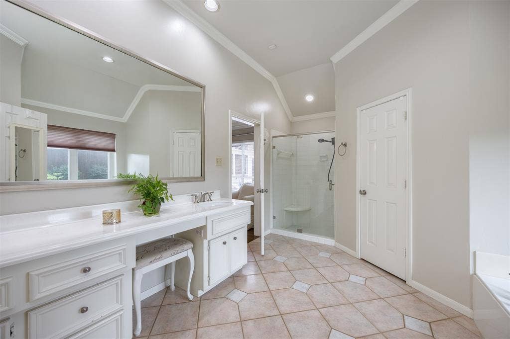 1717 Whitney Drive, Richardson, TX 75082 Spacious bathroom featuring a double vanity with ample storage, a framed mirror, and a glass-enclosed shower with a built-in bench