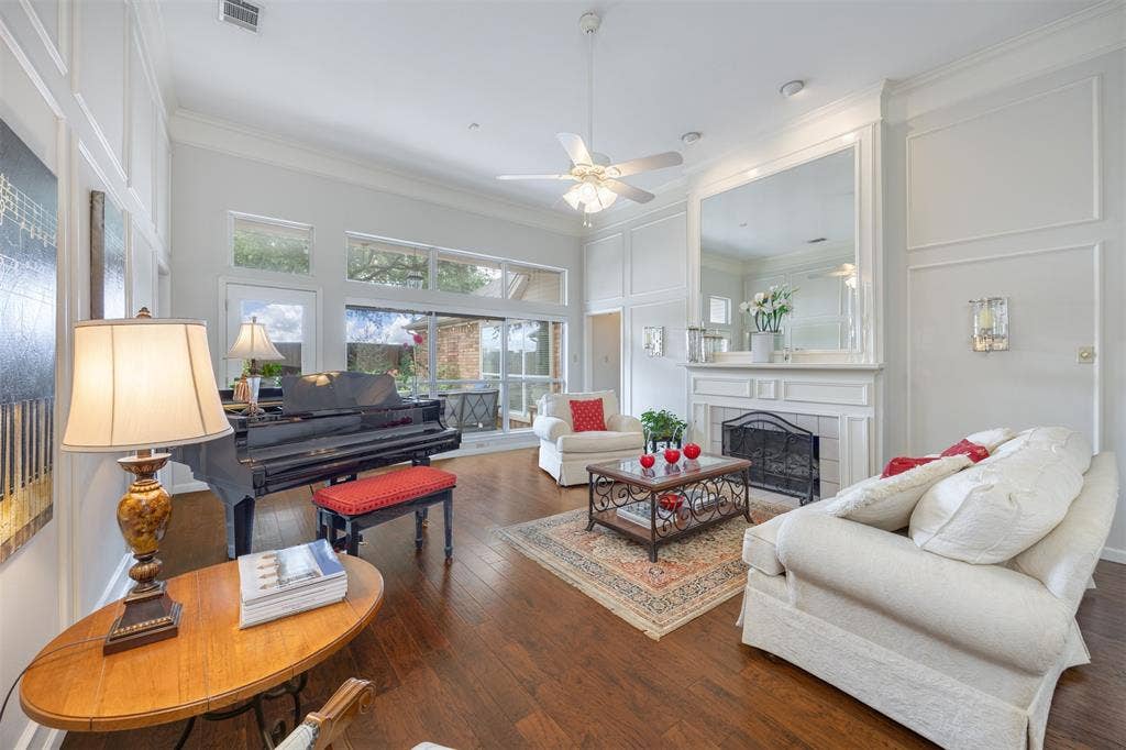 1717 Whitney Drive, Richardson, TX 75082 Spacious living area featuring high ceilings, wood-finish flooring, a decorative fireplace with a substantial mantel, and extensive natural light through large windows and sliding glass doors