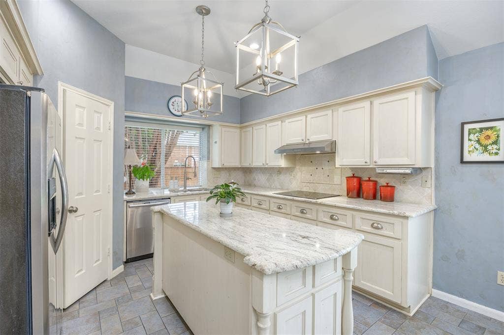 1717 Whitney Drive, Richardson, TX 75082 Kitchen featuring a center island with a light-toned countertop, white cabinetry with silver hardware, stainless steel appliances, and a tiled backsplash