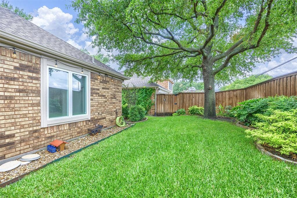 1717 Whitney Drive, Richardson, TX 75082 Expansive backyard featuring a mature tree, manicured lawn, and a privacy fence