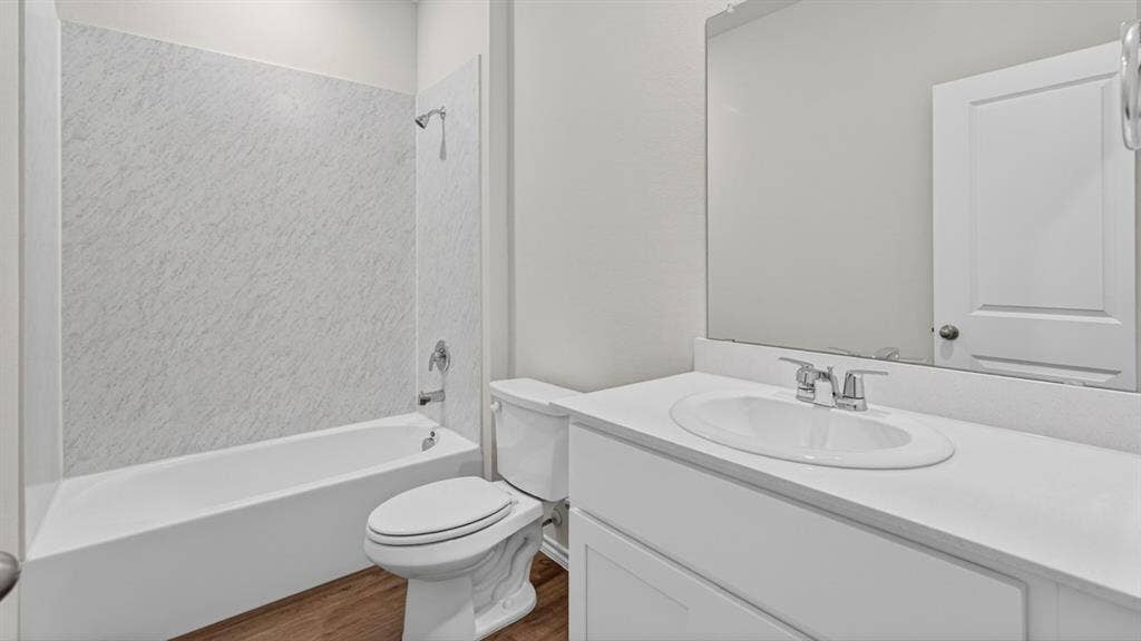 1933 Freeman Street, Tyler, TX 75704 Bathroom featuring a white vanity with an undermount sink, a large mirror, a white toilet, a white bathtub, and a shower with textured wall panels