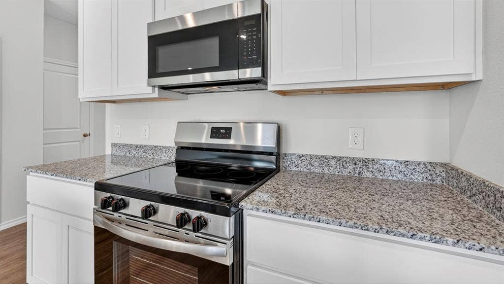 1933 Freeman Street, Tyler, TX 75704 Kitchen featuring granite countertops, white cabinetry, stainless steel range, and an over-the-range microwave