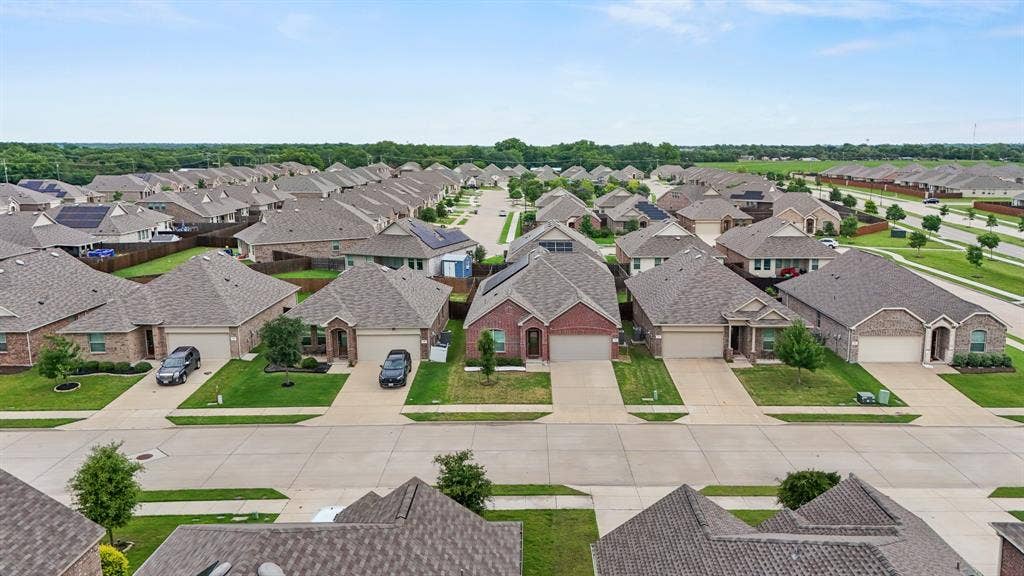 714 Stallings Drive, Princeton, TX 75407 Aerial perspective showcasing a residential neighborhood with uniform-style homes, each featuring a shingled roof, brick or stone facade, and an attached two-car garage