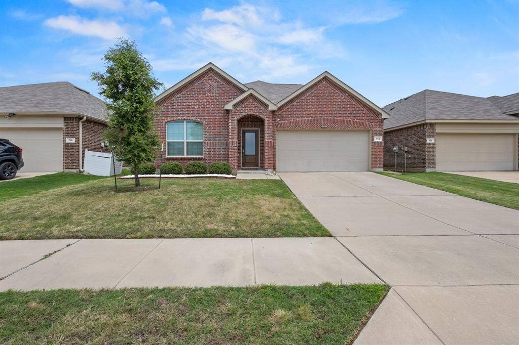 714 Stallings Drive, Princeton, TX 75407 Brick exterior featuring an arched entryway, integrated garage, and a concrete driveway