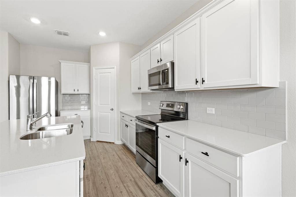 714 Stallings Drive, Princeton, TX 75407 Modern kitchen featuring white cabinetry, light-toned countertops, and wood-finish flooring