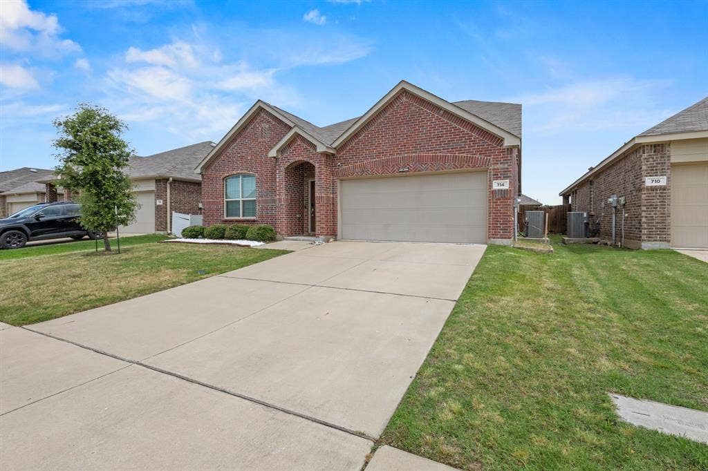 714 Stallings Drive, Princeton, TX 75407 Brick exterior with an arched entry, a two-car garage, and a concrete driveway
