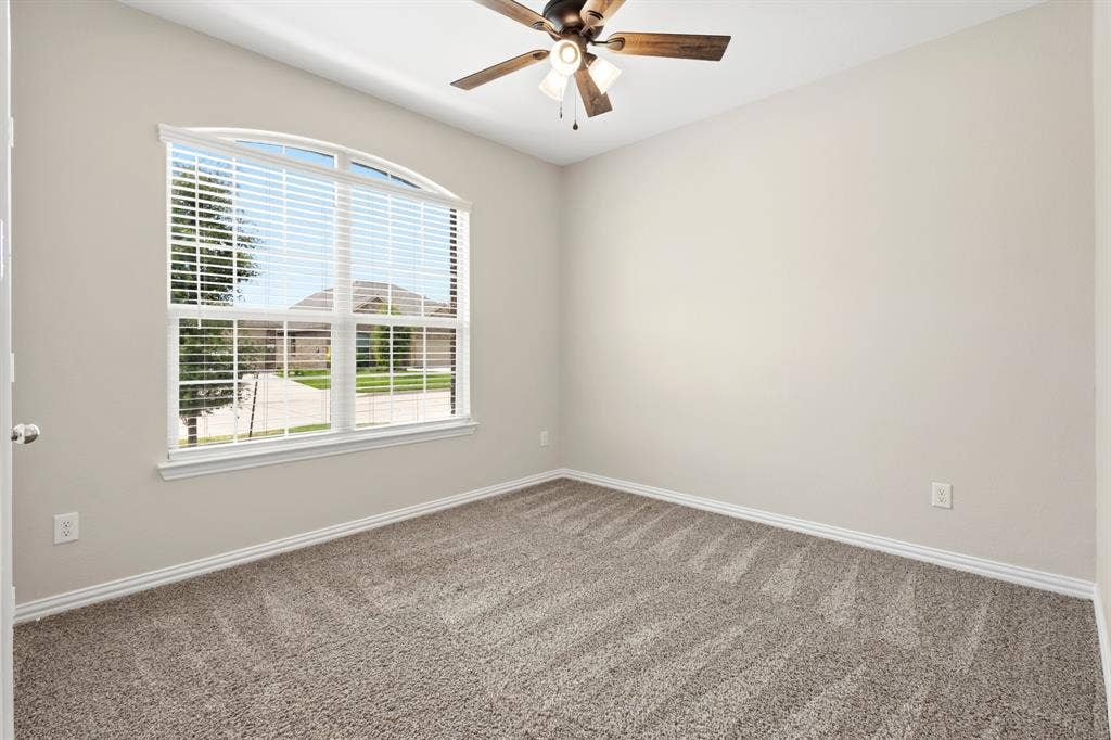 714 Stallings Drive, Princeton, TX 75407 Room featuring an arched window with blinds, neutral wall paint, and patterned carpet flooring