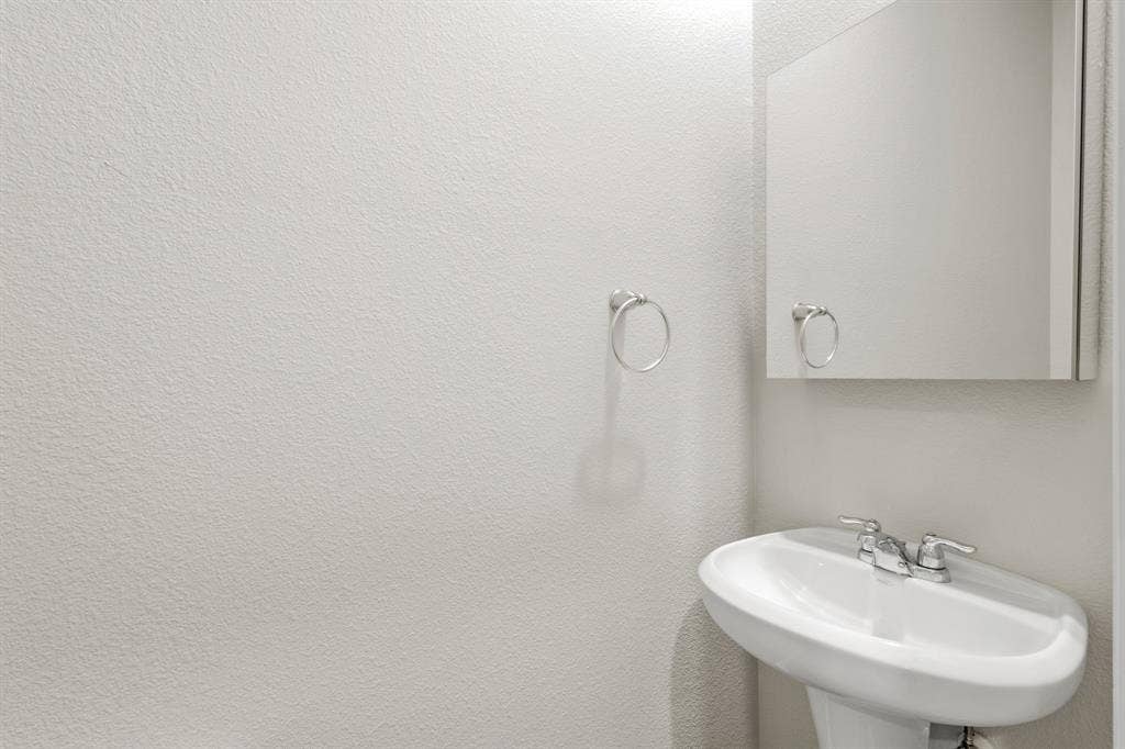 714 Stallings Drive, Princeton, TX 75407 Pedestal sink with chrome fixtures and an overhead mirrored medicine cabinet