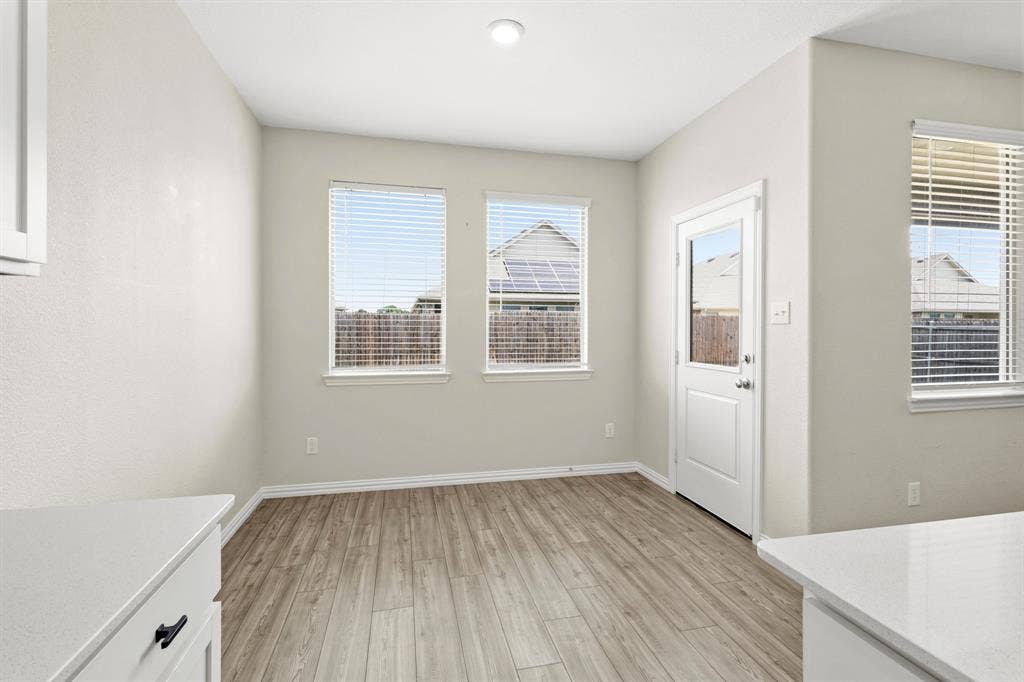 714 Stallings Drive, Princeton, TX 75407 Open-concept room featuring wood-finish flooring, two large windows, a white glass-panel door, and recessed lighting