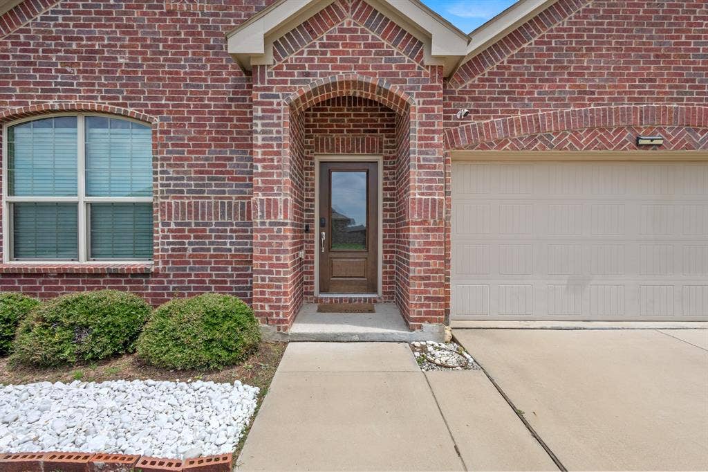714 Stallings Drive, Princeton, TX 75407 Brick facade featuring a recessed entry with an arched accent and a brown paneled door with glass insert