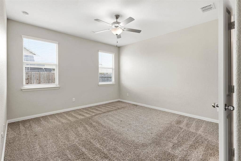 714 Stallings Drive, Princeton, TX 75407 Carpeted room featuring two double-hung windows with blinds, a ceiling fan with integrated lighting, and neutral wall paint