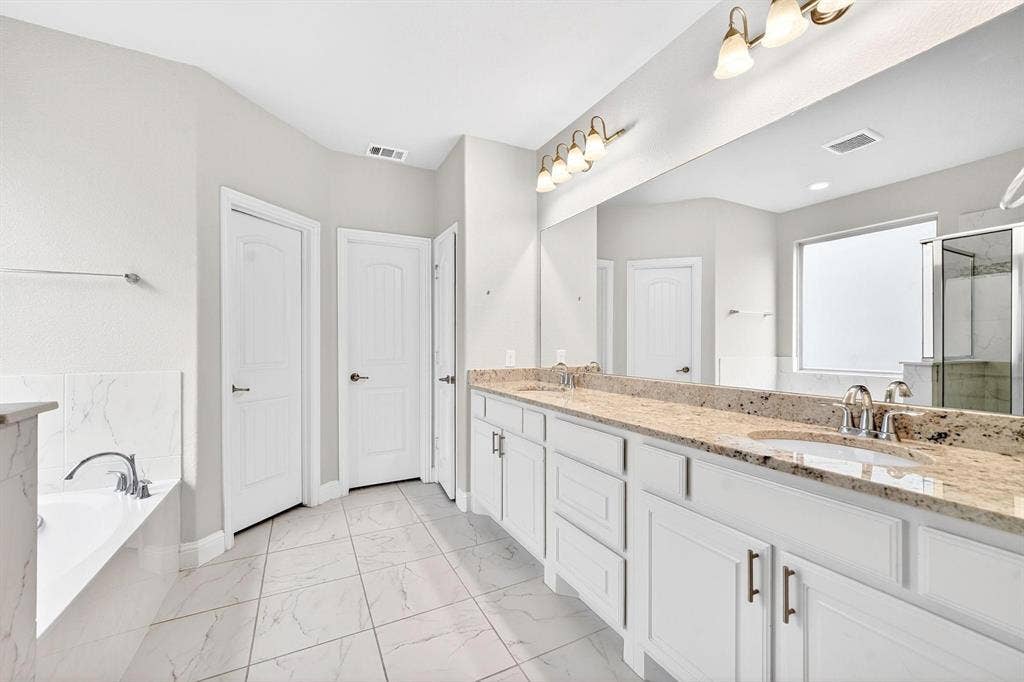 Double vanity with light granite countertops, white cabinetry, and brushed nickel hardware