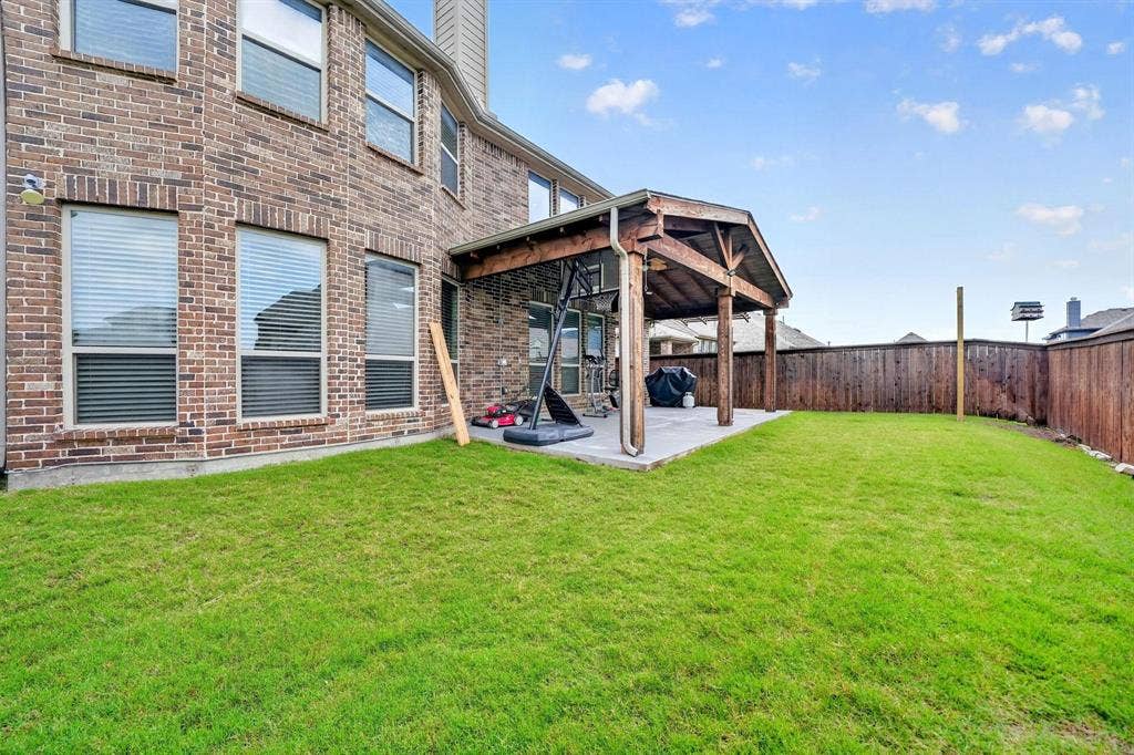 Expansive backyard featuring a covered patio with a vaulted wood ceiling, concrete flooring, and a privacy fence