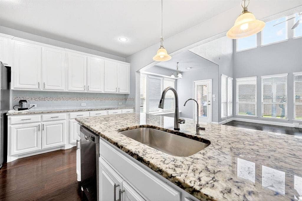 Kitchen featuring a large island with an undermount sink, granite countertops, white cabinetry, and wood-finish flooring