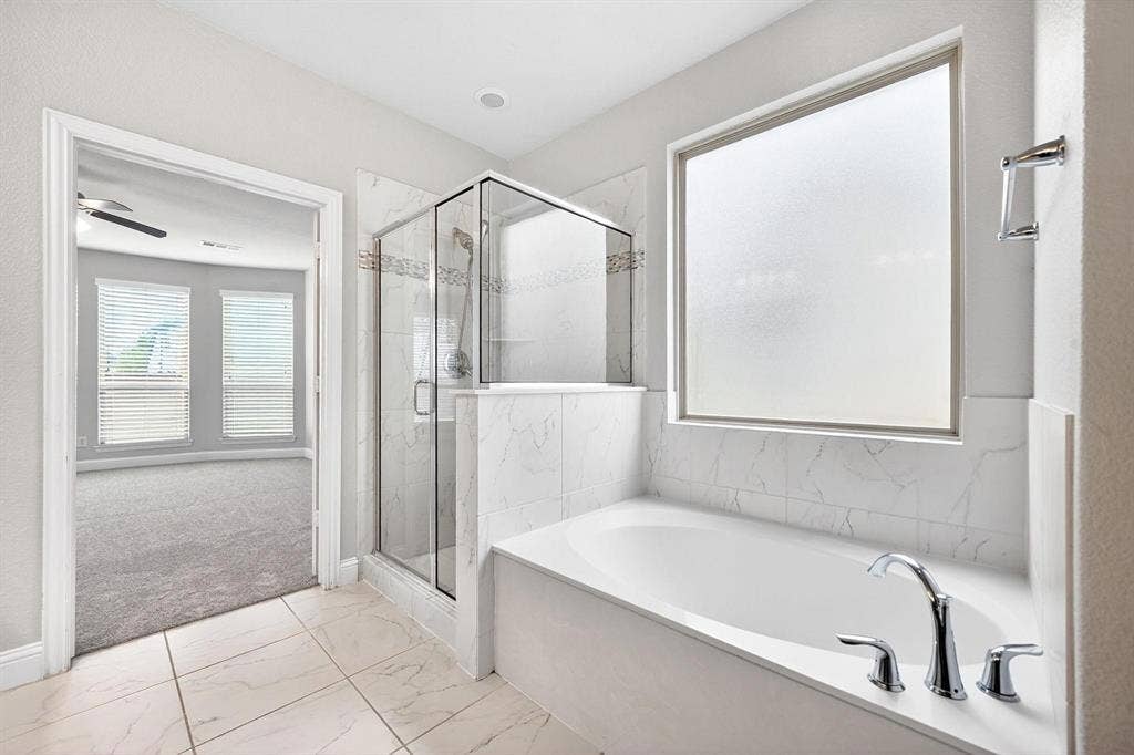 Contemporary bathroom featuring a built-in soaking tub with chrome fixtures, a glass-enclosed shower with tile surround, and an opaque privacy window