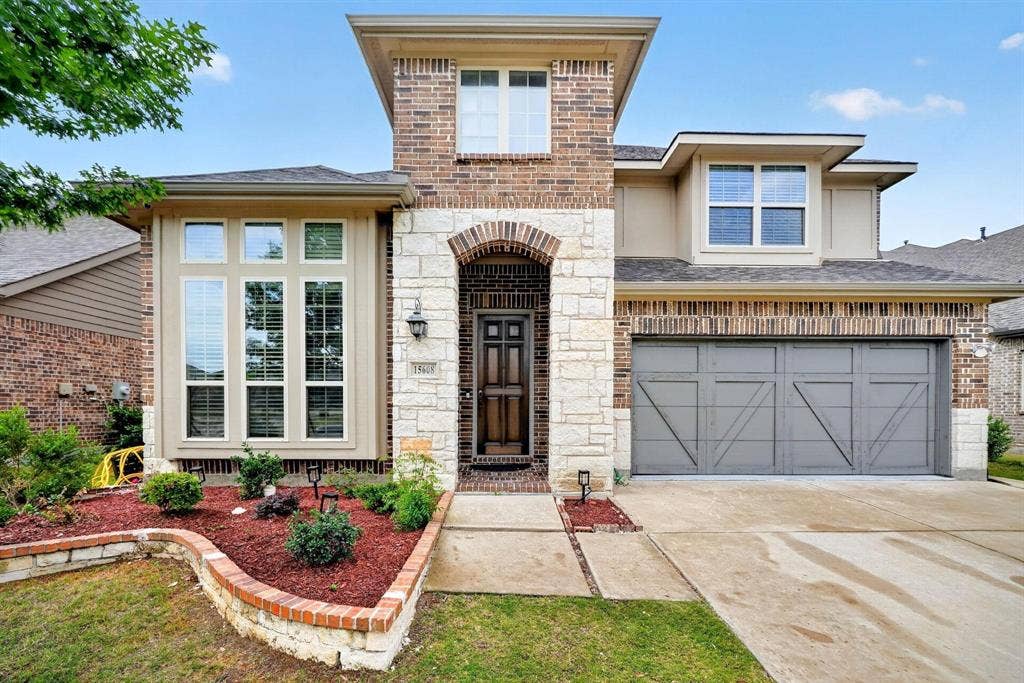 Brick and stone facade featuring a two-car garage with decorative paneling